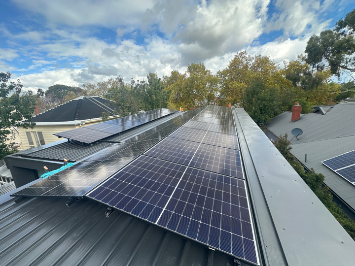 Solar panels on roof with slight tilt, blue sky with clouds in background. Solar pv system Installed by accredited solar retailer